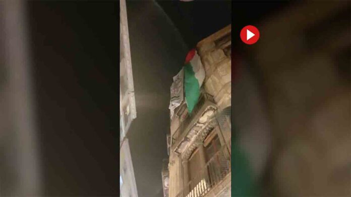 Cuelgan una gran bandera palestina en un edificio del Raval de un israelí